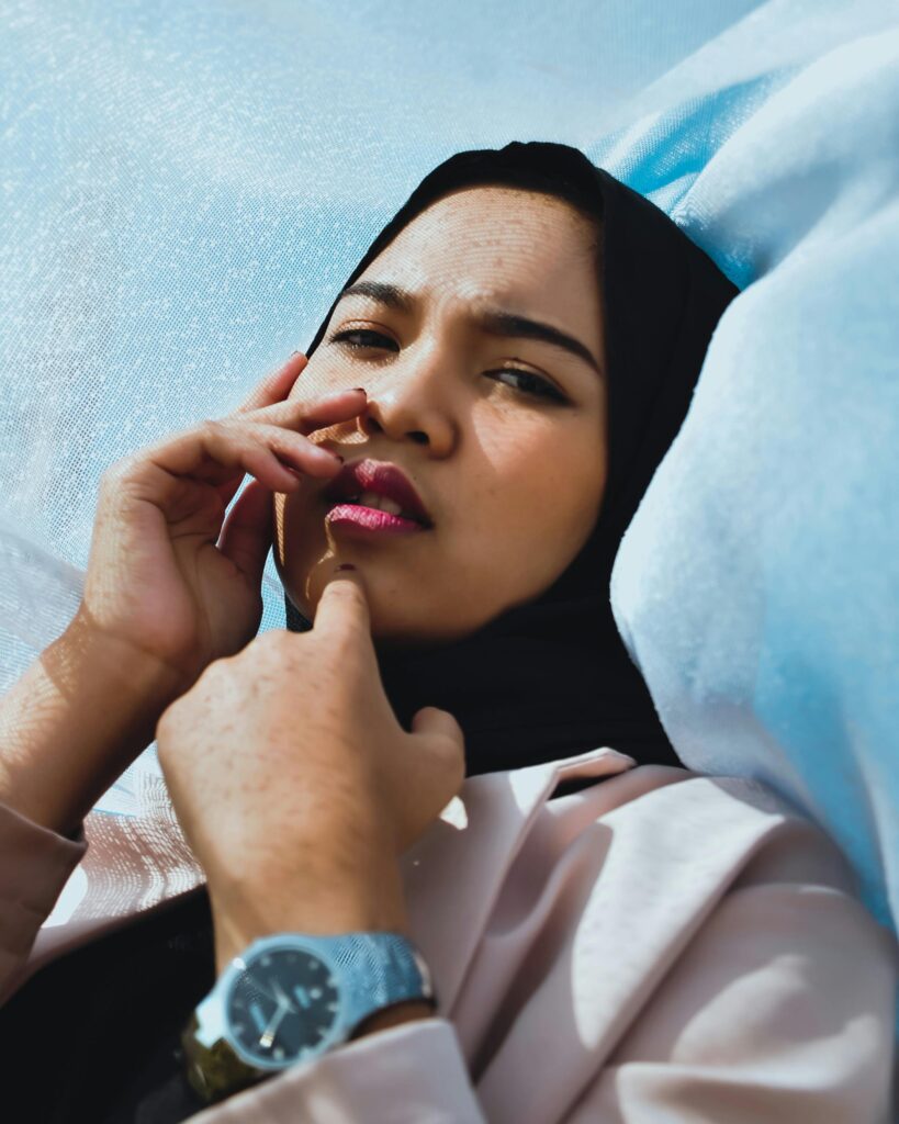 A thoughtful woman in a hijab lying down, reflecting and resting mid-day.