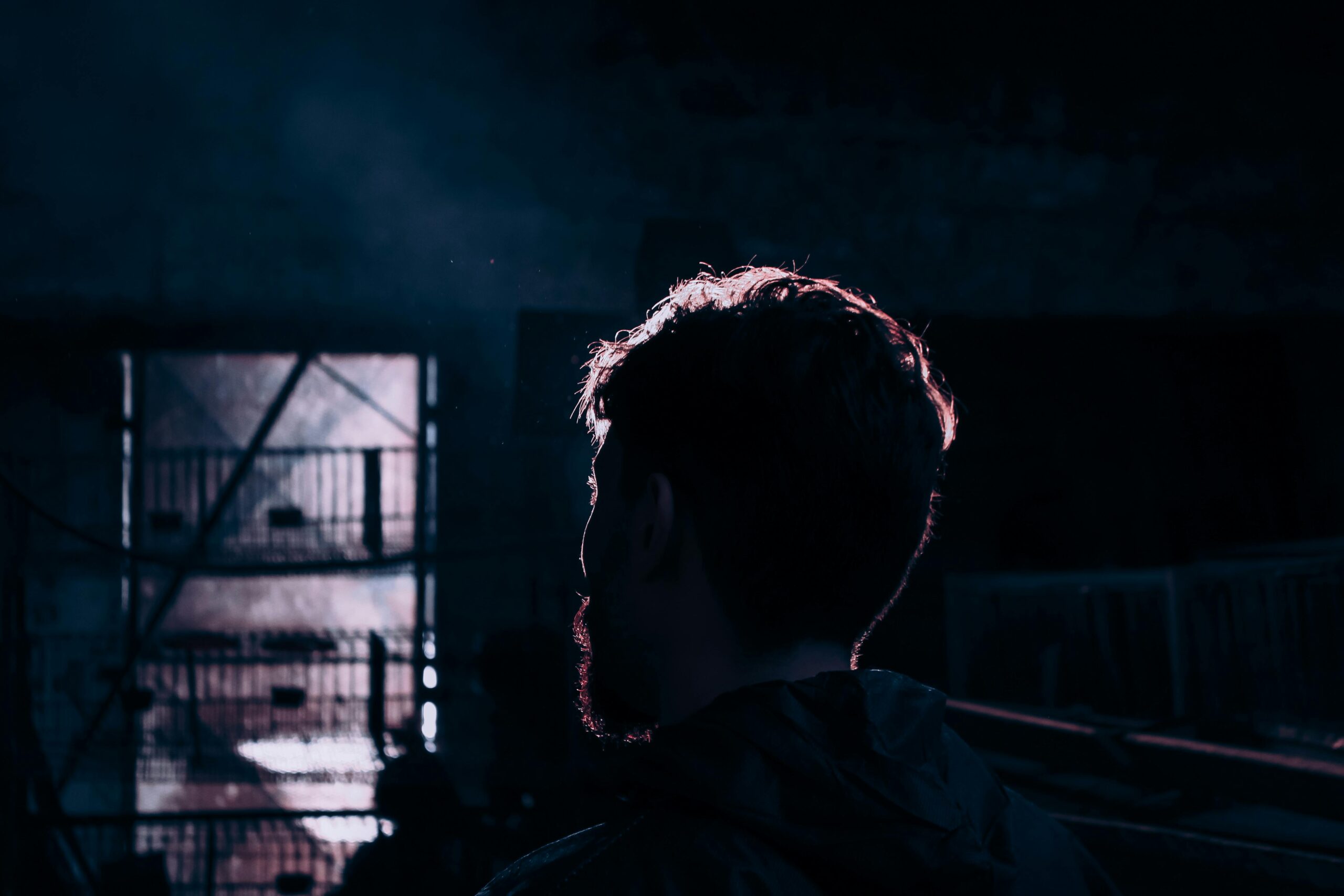 A silhouetted man stands in dramatic lighting creating a mysterious atmosphere.